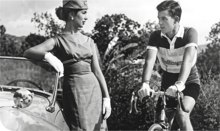 Ciclista de época junto a un automóvil clásico